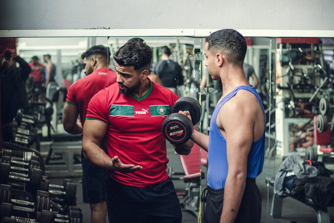 about-01 A fitness trainer guides a client in weight training at a well-equipped gym, emphasizing proper technique.